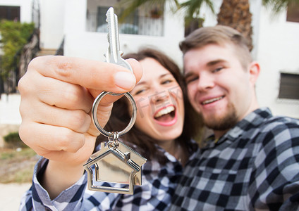 财产、房地产和公寓概念 — 快乐风趣的年轻夫妇展示他们新房的钥匙