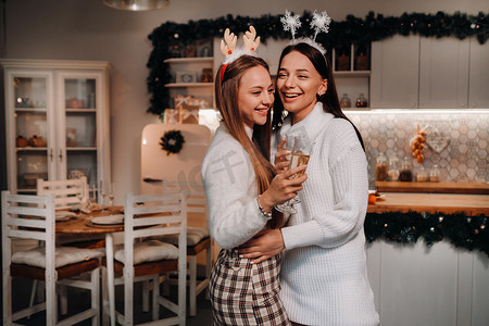 家庭环境摄影照片_圣诞节时，两个女孩在舒适的家庭环境中，手里拿着香槟。
