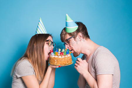 戴着纸帽子的怪异年轻夫妇女孩和男孩想要咬掉一块祝贺蛋糕。