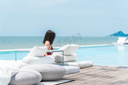 海边酒店摄影照片_泳池海边白色床上的女性泳装