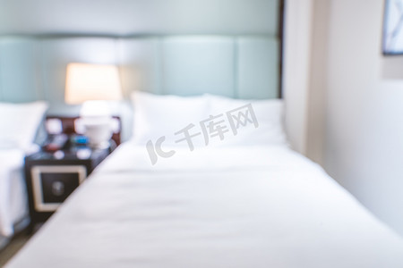 现代双人床摄影照片_干净舒适的现代酒店卧室内部配有双人床，抽象的散焦模糊与散景背景，豪华旅行的设计理念。