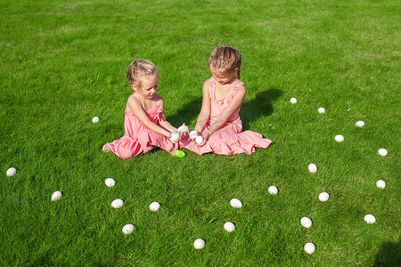 绿女孩摄影照片_可爱的小女孩在绿草上玩复活节彩蛋
