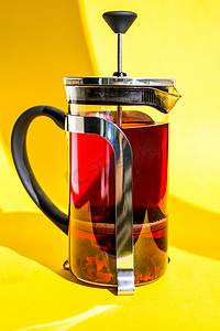 带热芙蓉茶的玻璃茶壶 新鲜酿造的辛辣果茶，配香草、玫瑰花、黄色背景的热健康饮料，带文字复制空间