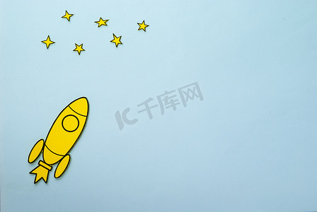 带火焰火箭摄影照片_带助推器火焰的黄色火箭飞向星星