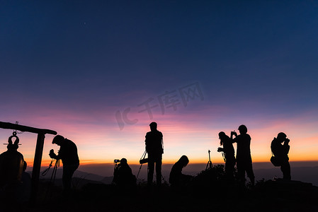 摄影师剪影摄影照片_悬崖上的摄影师剪影反对多彩的黄昏天空