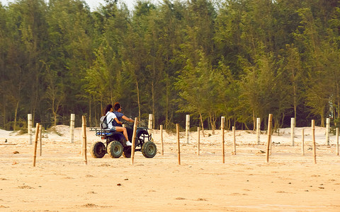 夏季日落时，蜜月夫妇在沙海海滩沿海公路上骑电动三轮车（三轮三轮摩托车）。