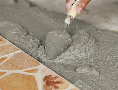 家杂摄影照片_杂工铺设瓷砖，用砂浆抹平