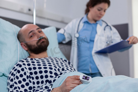 病人躺在床上，手指上戴着医用血氧计