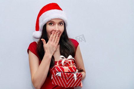 特写圣诞照片，印象深刻的女孩用红色连衣裙和圣诞老人​​帽子的礼盒尖叫哇天哪