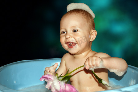小男孩在洗澡，手里拿着花。