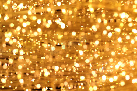 金黄色背景摄影照片_散景背景金黄色五颜六色的圣诞快乐，新年快乐散景灯光照耀在夜间背景，散景闪光灯，金色豪华背景纹理，闪闪发光的壁纸