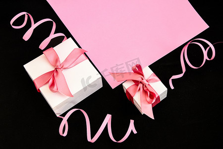 粉色和黑色背景上带有粉色丝带的礼物盒