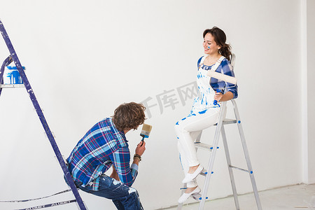 团队合作、翻新和维修概念 — 坐在梯子上涂着油漆的男人和女人