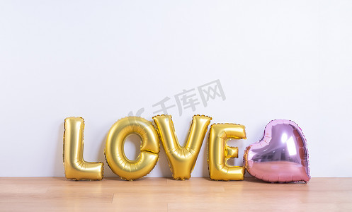 婚礼墙摄影照片_情人节、母亲节设计理念 — 浅色木地板和白墙背景上带有爱字形状的漂亮气球，特写