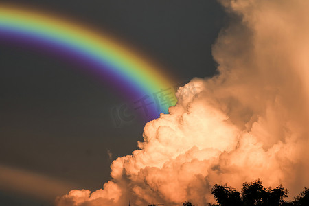 日落时分摄影照片_彩虹在雨后出现在天空中，并在日落时分出现