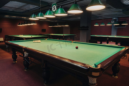 台球俱乐部里有绿色表面和球的台球桌。台球比赛