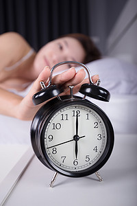 女人睡觉摄影照片_女人睡觉并早上醒来关掉闹钟