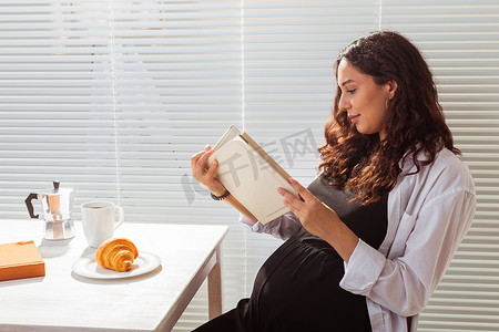孕妇在吃早饭时正在看书。
