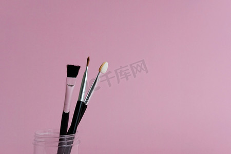 粉色柔和背景瓶子上的一组化妆刷工具