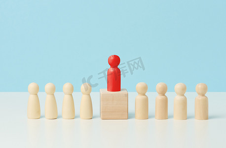 白色桌子上的木制小矮人，红色站在木制立方体上。