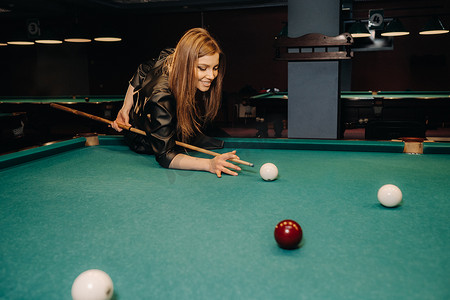 漂亮的桌面背景摄影照片_一个手里拿着球杆的女孩在台球俱乐部里击球。俄罗斯台球