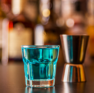 流行的蓝色饮料在酒吧的背景上用瓶子射击 kamikaze，这是一种清爽的饮料