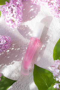 本子样机摄影照片_粉红色的香水瓶和淡紫色的树枝光影。