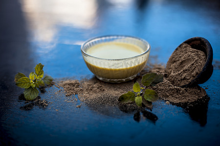 有益的摄影照片_Ayurvedic 草本 brahmi 或 Waterhyssop，将其有益的糊状物放入玻璃碗中，并在木质表面上涂上粉末。