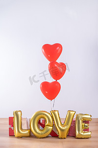 情人节、母亲节、生日设计理念 — 心形氦气球，浅色木地板上装有礼盒，白墙背景，特写。