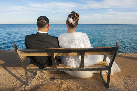 新娘和新郎坐在海边的长椅上