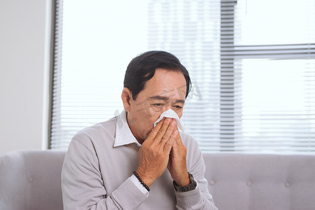 老人得了流感，用纸巾擦鼻子。
