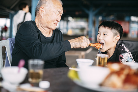 亚洲老爷爷在餐厅喂孙子