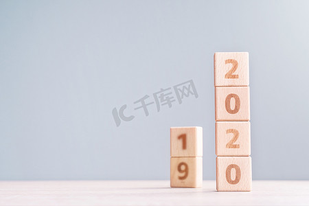 摘要 2020 年和 2019 年新年倒计时设计理念 — 木桌上的木块立方体和低饱和度蓝色背景，特写，复制空间。