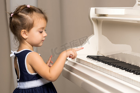 白色古典摄影照片_这个女孩在白色的三角钢琴前。