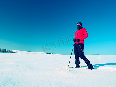 冬季衣服摄影照片_穿着雪鞋的冬季游客在雪地里行走。