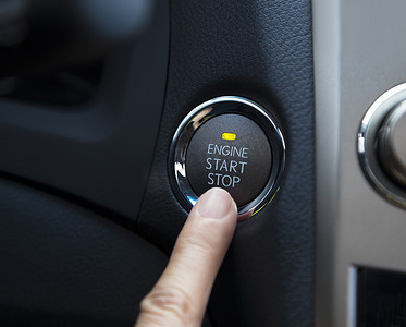 手指按下汽车的发动机启动停止按钮