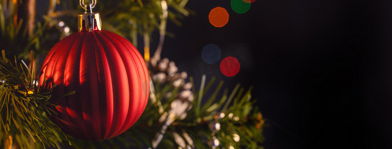 点摄影照片_美丽的圣诞装饰概念，挂在圣诞树上的小玩意，闪闪发光的光点，模糊的深黑色背景，宏观细节，特写。