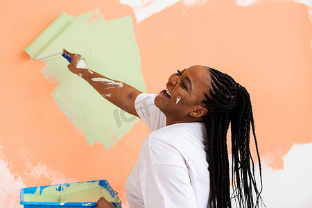 黑人妇女粉刷新家的墙壁。