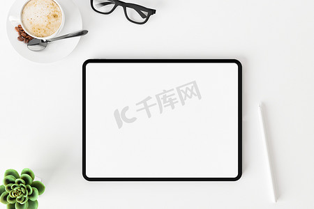 白色办公桌上空白屏幕平板电脑的顶部视图