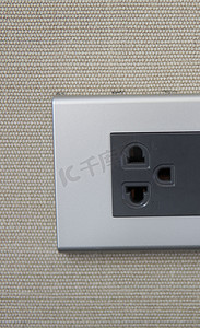 黄色墙壁上的灰色通用电源插座插头。