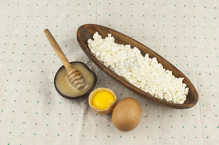黄金碗摄影照片_木碗里的干酪，圆点背景上有两个鸡蛋和蜂蜜。