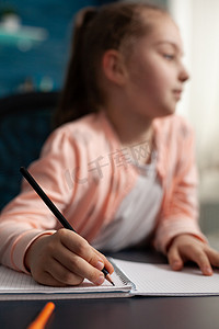 学习在线课程的小女学生在数学作业中的特写