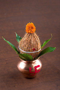 铜卡拉什与椰子和芒果叶与木制背景上的花卉装饰。