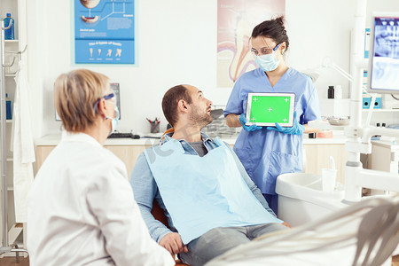 本子样机摄影照片_生病的病人在与口腔高级医生交谈时看着触摸屏小工具