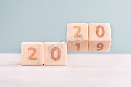 摘要 2020 年和 2019 年新年倒计时设计理念 — 木桌上的木块立方体和低饱和度绿色背景，特写，复制空间。
