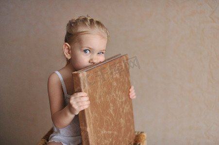 一个小女孩拿着一本用天然棕色皮革制成的相册。