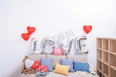 气球墙摄影照片_情人节，母亲节惊喜设计理念，将爱情气球和礼物放在背景为白墙的沙发上。