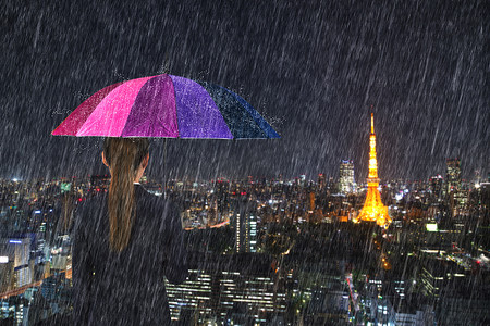 下着雨摄影照片_东京市女商人拿着五颜六色的雨伞，下着雨