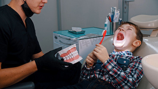 刷牙的小男孩摄影照片_一个张开嘴巴接受牙科治疗的小男孩-讨论卫生和刷牙
