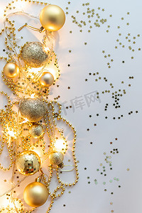 圣诞假期作文、金色圣诞装饰品的顶视图和黄色背景上带灯的花环，带有文本复制空间。